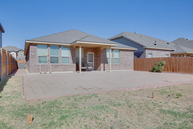 back of house with a fenced backyard, a patio, and brick siding