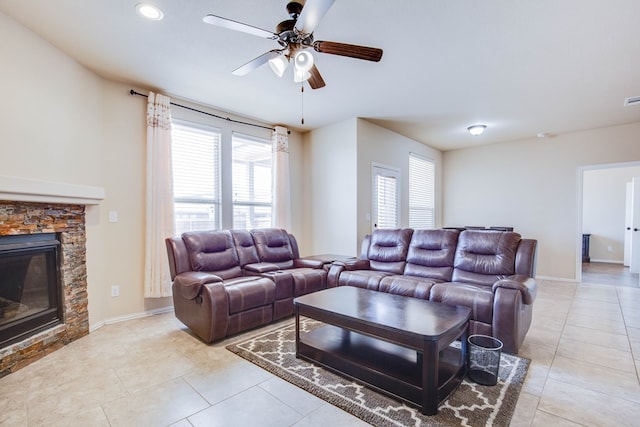 living area with a ceiling fan, light tile patterned floors, a healthy amount of sunlight, and a fireplace