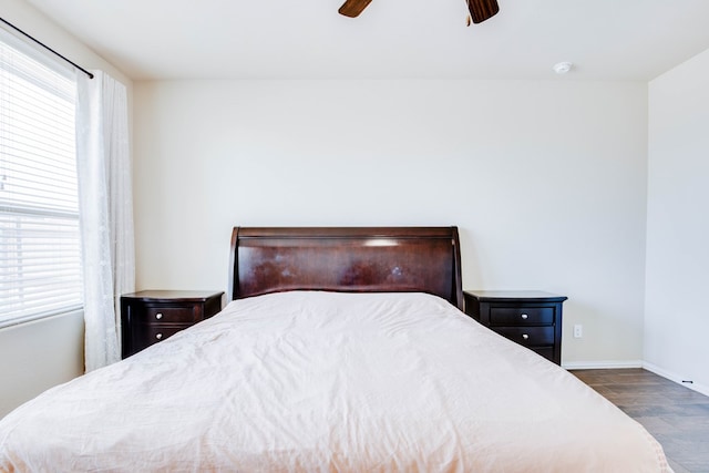 bedroom with baseboards, a ceiling fan, dark wood-style floors, and multiple windows