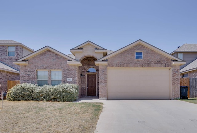 view of front of home with brick siding, a garage, fence, and driveway