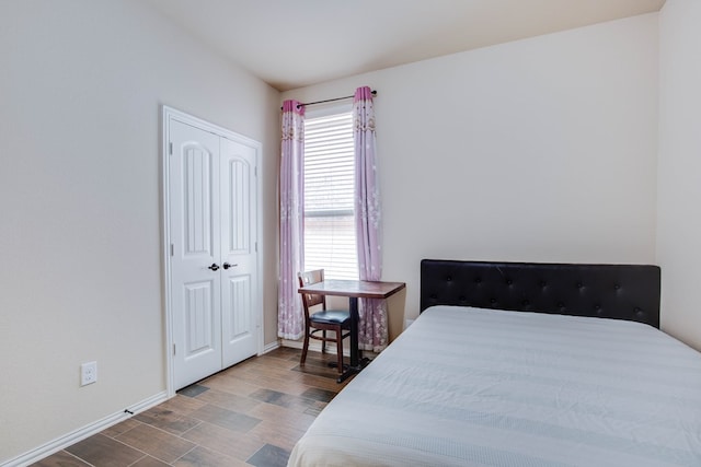 bedroom with baseboards, wood finished floors, and a closet