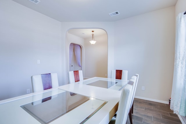 dining area featuring arched walkways, baseboards, wood finish floors, and visible vents