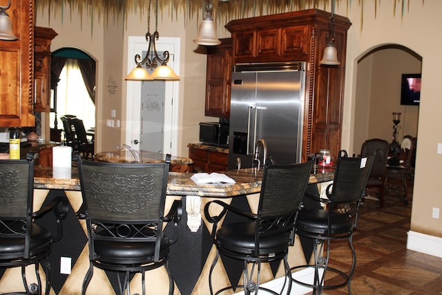173 W 87th St, Odessa, TX 79764 - kitchen with stainless steel built in refrigerator, arched walkways, and a breakfast bar area