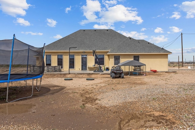 1758 N Fortune 500 Dr, Odessa, TX 79764 - back of property featuring a trampoline, stucco siding, and a shingled roof