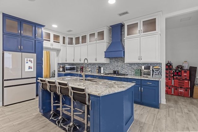 1758 N Fortune 500 Dr, Odessa, TX 79764 - kitchen with custom exhaust hood, visible vents, a sink, blue cabinetry, and appliances with stainless steel finishes