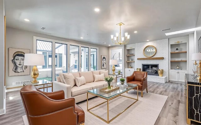 living area featuring built in shelves, wood finished floors, visible vents, and a chandelier