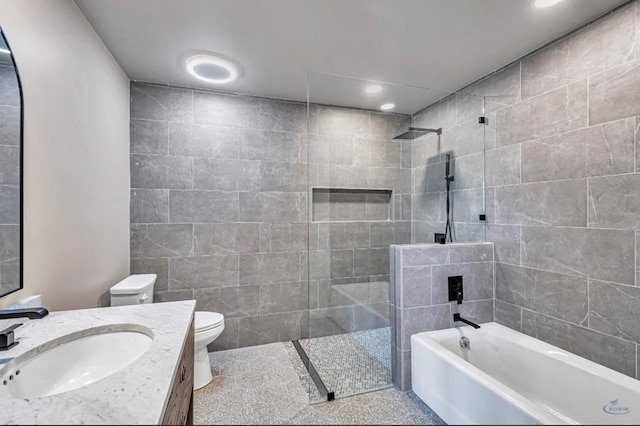 full bath featuring toilet, a tub, tile walls, walk in shower, and vanity