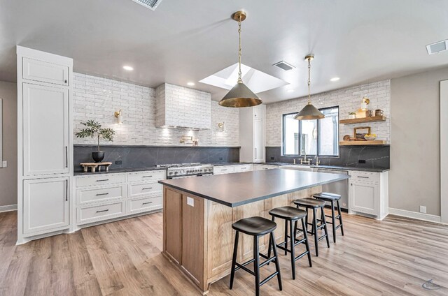 kitchen featuring dark countertops, visible vents, light wood-style flooring, and a kitchen breakfast bar