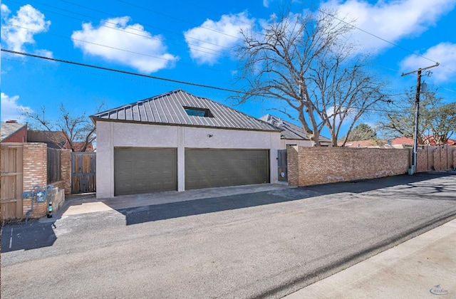 garage with driveway, fence, and a gate