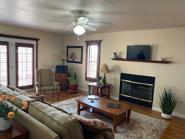 1413 S Oak St, Pecos, TX 79772 - living room with a glass covered fireplace, ceiling fan, wood finished floors, and a wealth of natural light
