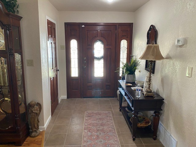 1413 S Oak St, Pecos, TX 79772 - foyer entrance with light tile patterned floors, baseboards, and a textured wall