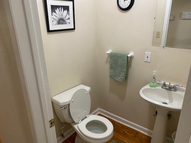 1413 S Oak St, Pecos, TX 79772 - half bathroom with a sink, baseboards, toilet, and wood finished floors