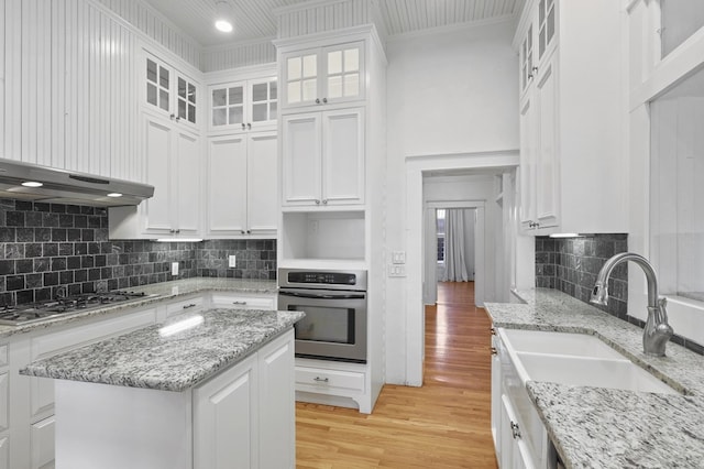 201 S Front St, Fort Davis, TX 79734 - kitchen featuring appliances with stainless steel finishes, white cabinetry, light wood finished floors, crown molding, and backsplash