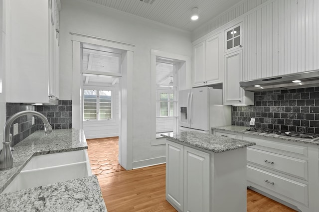 201 S Front St, Fort Davis, TX 79734 - kitchen featuring white refrigerator with ice dispenser, stainless steel gas stovetop, white cabinets, decorative backsplash, and ornamental molding