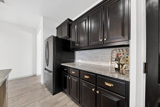7410 W Pile Ranch Rd, Odessa, TX 79765 - kitchen with freestanding refrigerator, backsplash, light wood-style flooring, and light stone countertops