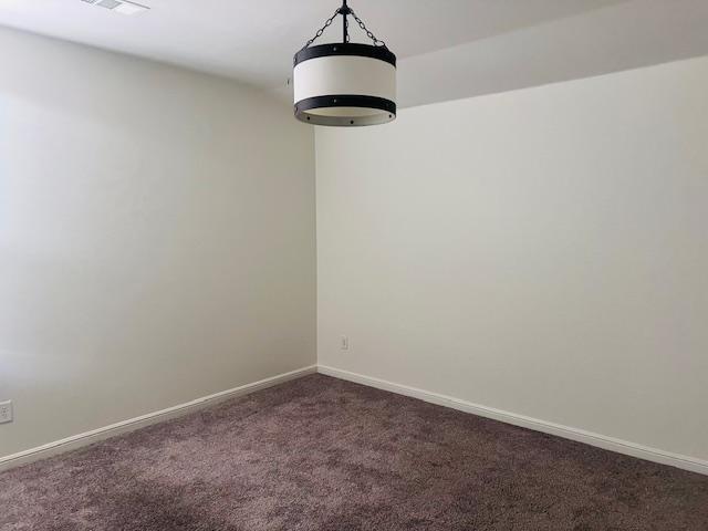 7410 W Pile Ranch Rd, Odessa, TX 79765 - spare room with dark carpet and baseboards