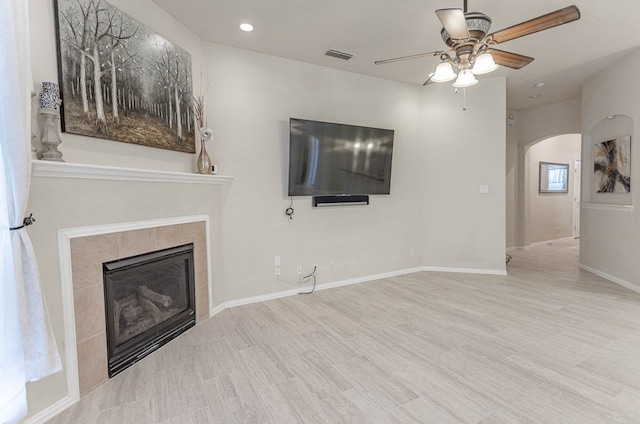 6921 Stonehenge Rd, Odessa, TX 79765 - unfurnished living room featuring a ceiling fan, a fireplace, arched walkways, wood finished floors, and recessed lighting