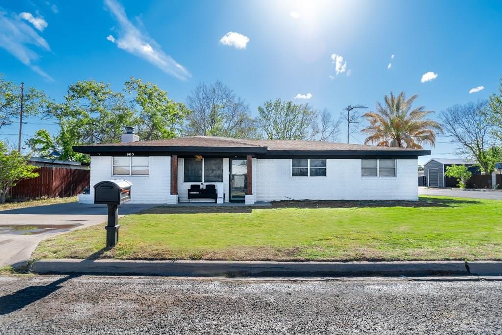 ranch-style house featuring fence and a front lawn