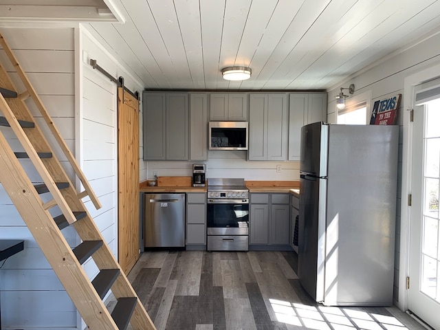 104 Low Meadow Pt, Fort Davis, TX 79734 - kitchen featuring dark wood-style flooring, appliances with stainless steel finishes, a barn door, wooden counters, and gray cabinetry