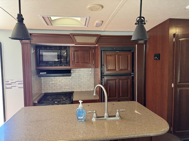 287 Fulcher Rd, Terlingua, TX 79852 - kitchen with black microwave, tasteful backsplash, decorative light fixtures, and a sink