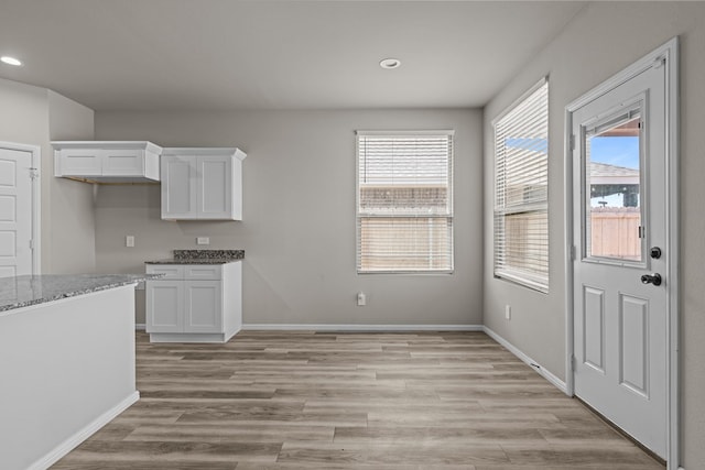 kitchen with baseboards, recessed lighting, white cabinets, light stone counters, and light wood finished floors