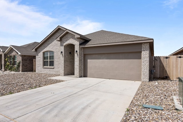 ranch-style home featuring fence, an attached garage, a shingled roof, brick siding, and concrete driveway