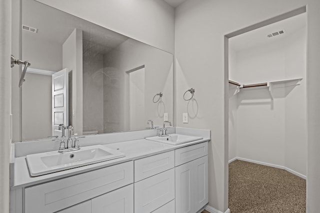 full bathroom with a sink, a walk in closet, double vanity, and visible vents