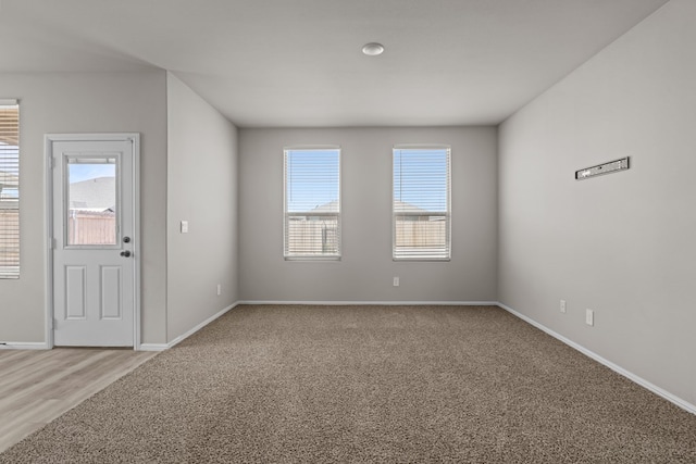 spare room featuring baseboards and light carpet