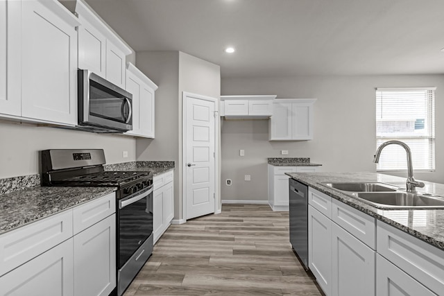 kitchen featuring a sink, stainless steel appliances, recessed lighting, white cabinetry, and light wood-type flooring