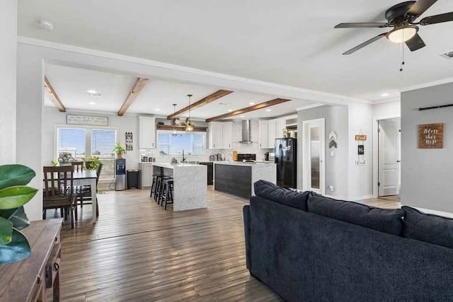 living room featuring ornamental molding, ceiling fan, sink, wood-type flooring, and beam ceiling