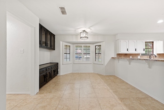 20 Sunnygrove Dr, Odessa, TX 79761 - kitchen with a breakfast bar area, white cabinets, and light tile patterned floors