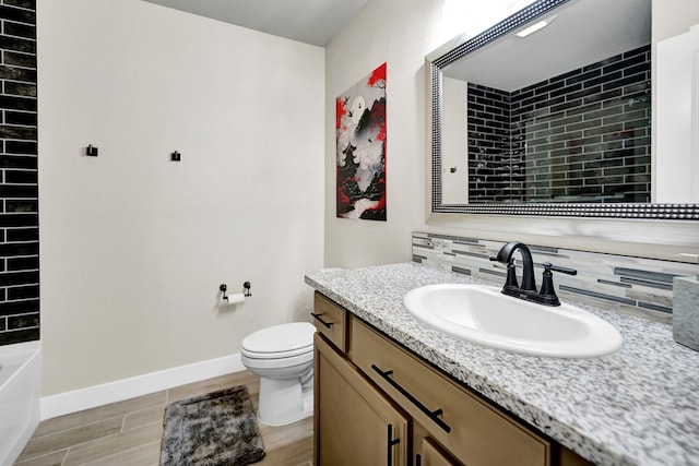 full bathroom featuring wood tiled floors, tasteful backsplash, toilet, baseboards, and vanity