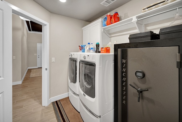 washroom featuring cabinet space, washing machine and dryer, baseboards, and light wood finished floors