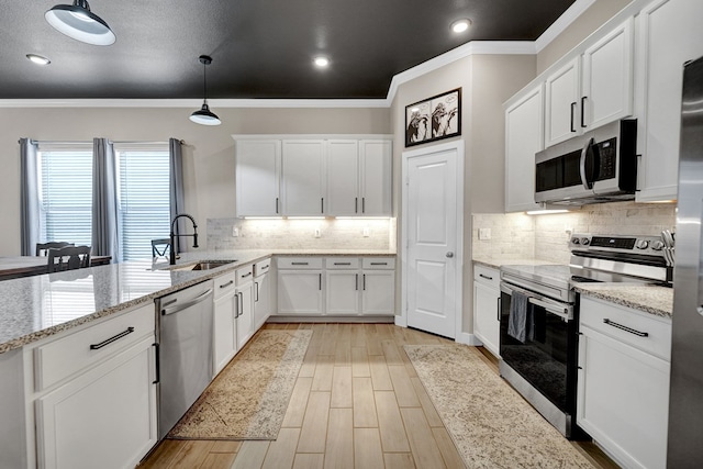 kitchen with stainless steel appliances, a sink, crown molding, white cabinetry, and light wood-style flooring