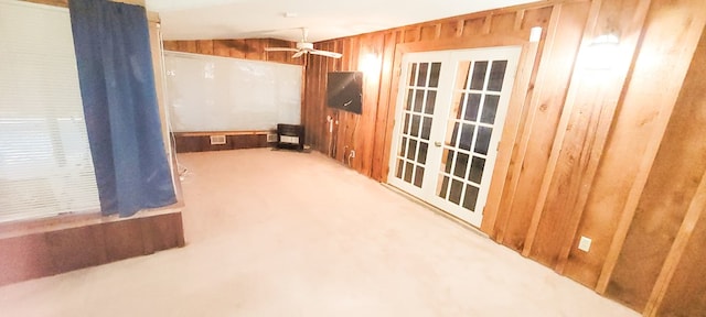 spare room with ceiling fan, wood walls, and light carpet