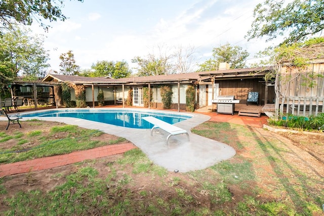 view of pool with grilling area, a patio, and a diving board