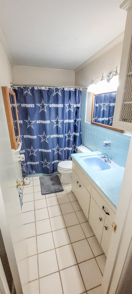 bathroom featuring backsplash, tile patterned floors, vanity, crown molding, and toilet