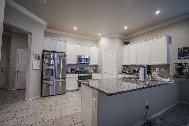 1322 E 89th St, Odessa, TX 79765 - kitchen with stainless steel appliances, decorative backsplash, dark stone countertops, white cabinetry, and a peninsula
