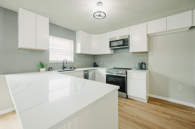 1613 E 52nd St, Odessa, TX 79762 - kitchen featuring appliances with stainless steel finishes, a sink, light stone countertops, a peninsula, and tasteful backsplash