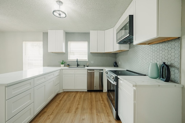 1613 E 52nd St, Odessa, TX 79762 - kitchen featuring dishwasher, electric range oven, a sink, a peninsula, and light wood finished floors