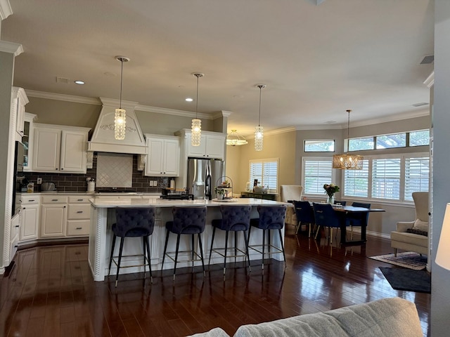 5 Muirfield Dr, Odessa, TX 79762 - kitchen featuring premium range hood, dark wood-style flooring, stainless steel fridge with ice dispenser, a kitchen bar, and ornamental molding