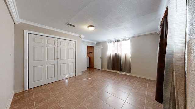 unfurnished bedroom featuring a closet, tile patterned flooring, a textured ceiling, and ornamental molding