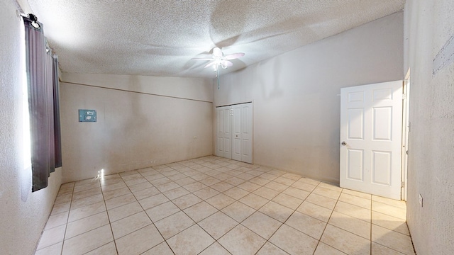 unfurnished room with light tile patterned floors, a textured ceiling, vaulted ceiling, and ceiling fan