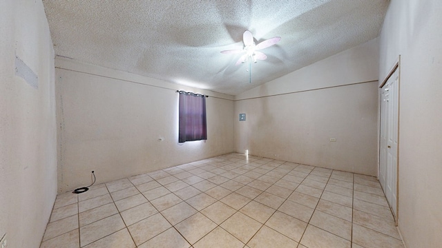 tiled empty room featuring ceiling fan, a textured ceiling, and vaulted ceiling