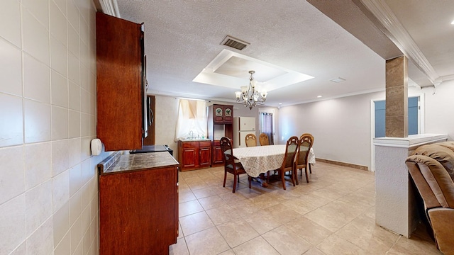 dining area featuring a raised ceiling, crown molding, a chandelier, a textured ceiling, and tile walls