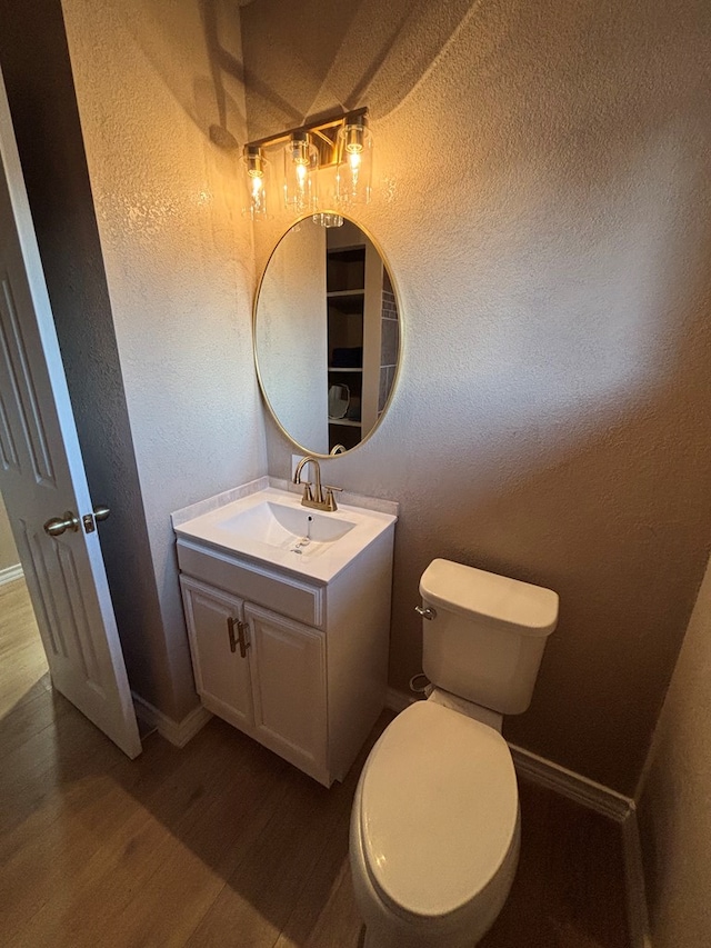 314 SW 11th Pl, Andrews, TX 79714 - half bath featuring a textured wall, wood finished floors, vanity, toilet, and baseboards