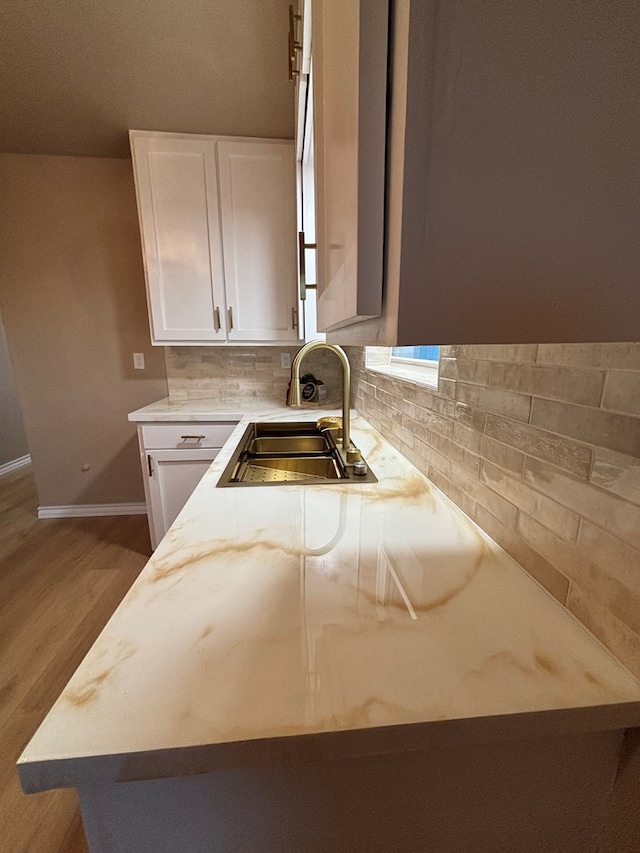 314 SW 11th Pl, Andrews, TX 79714 - kitchen featuring a sink, wood finished floors, white cabinetry, baseboards, and light countertops