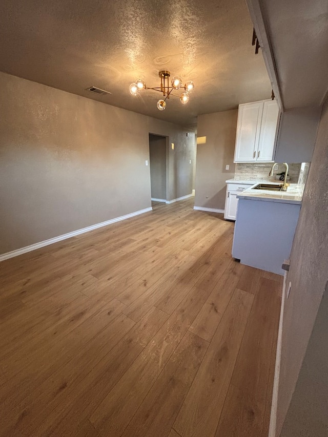 314 SW 11th Pl, Andrews, TX 79714 - kitchen with a sink, white cabinetry, light wood finished floors, light countertops, and baseboards