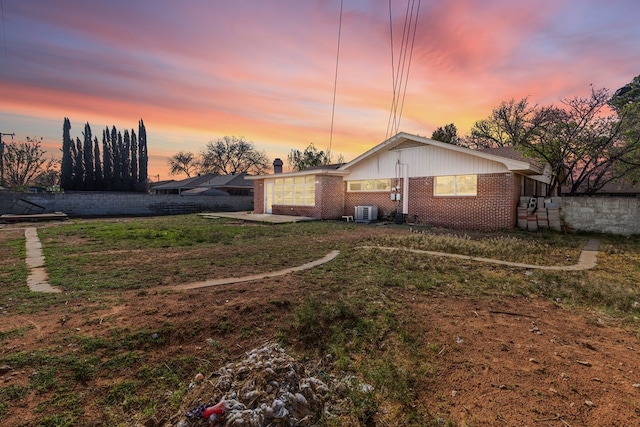 2616 E 21st St, Odessa, TX 79761 - back of house featuring brick siding, central air condition unit, a yard, a chimney, and a garage
