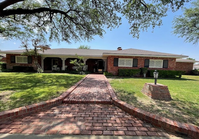 ranch-style house featuring brick siding, a chimney, and a front lawn